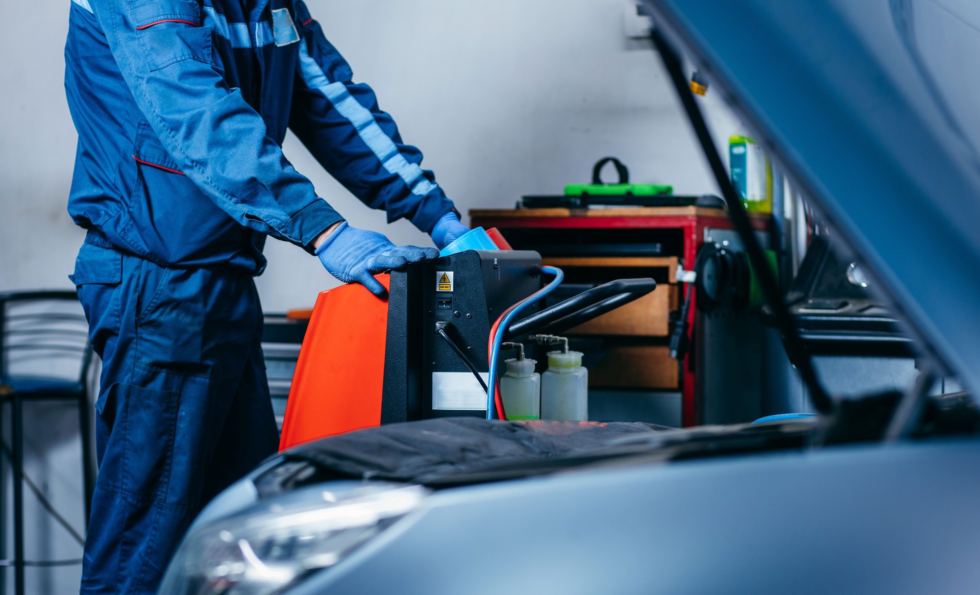 Close up hands of car mechanic using air conditioning system in auto service