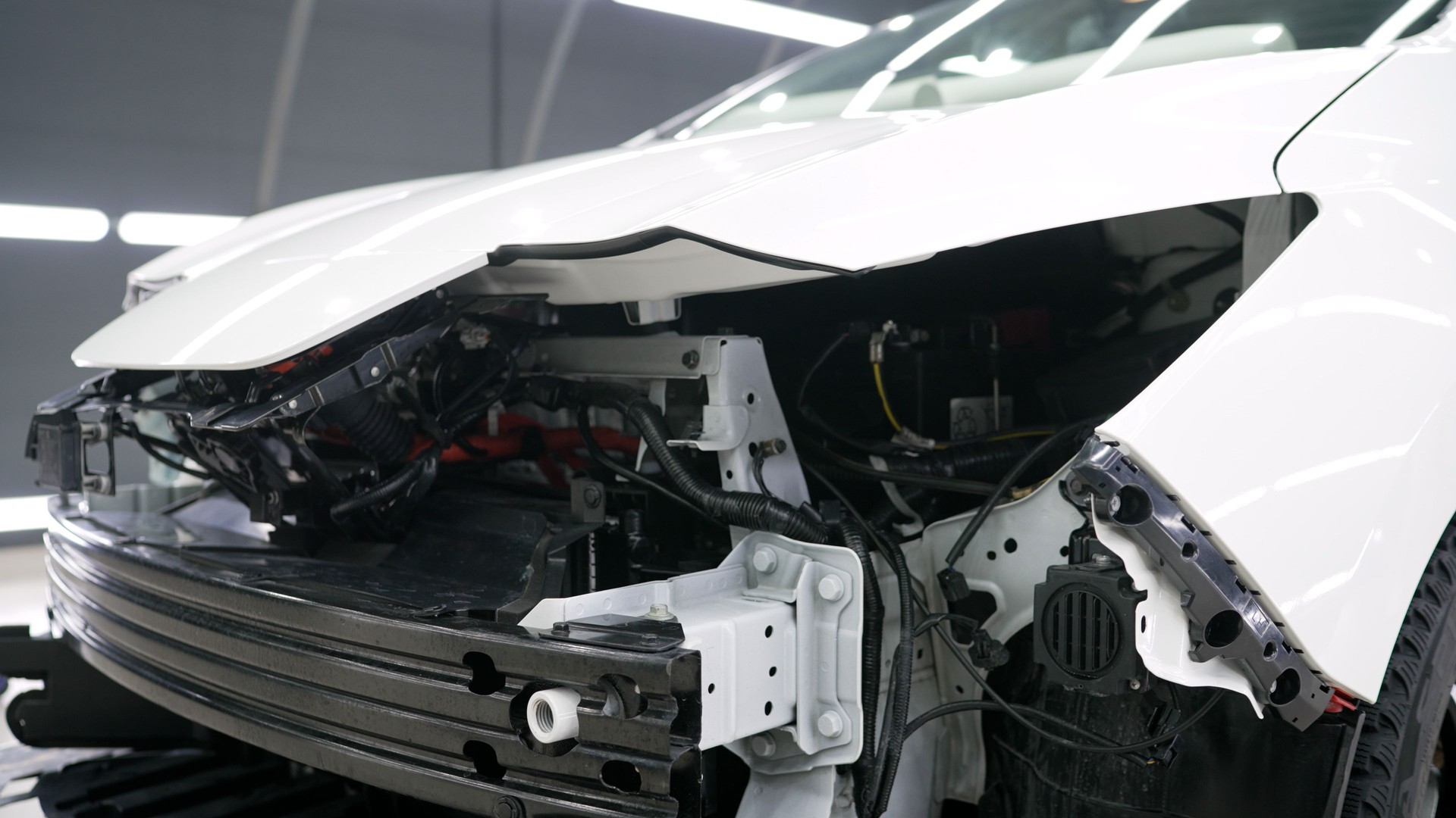 The front of the electric vehicle without a bumper. Electric car being repaired. Electric vehicle repair
