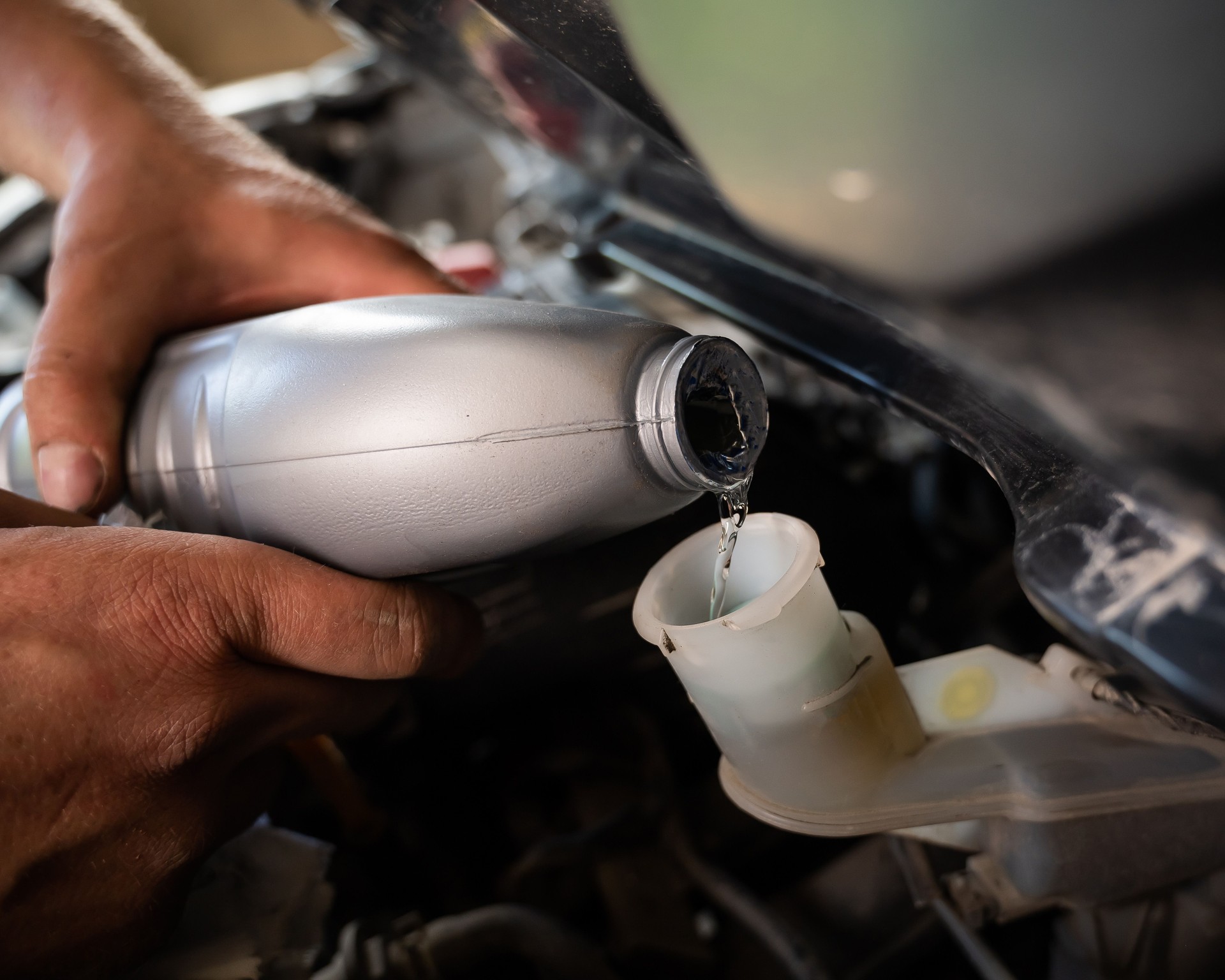 An auto mechanic pours brake fluid into the car
