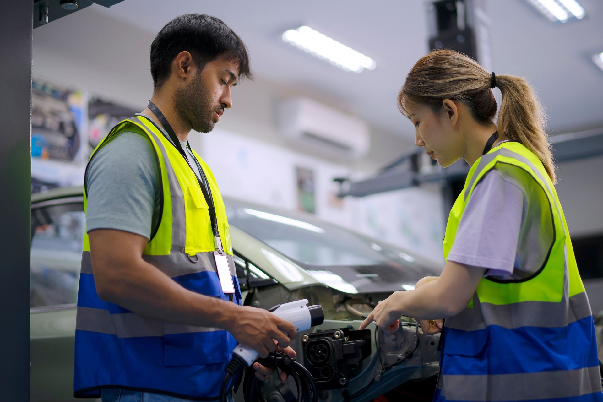 Mechanics are working at EV car workshop.